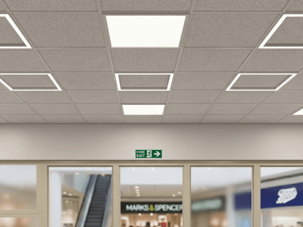 Close up of LED edge lit panel lights installed in a grid ceiling in a shop with large windows in a shopping centre