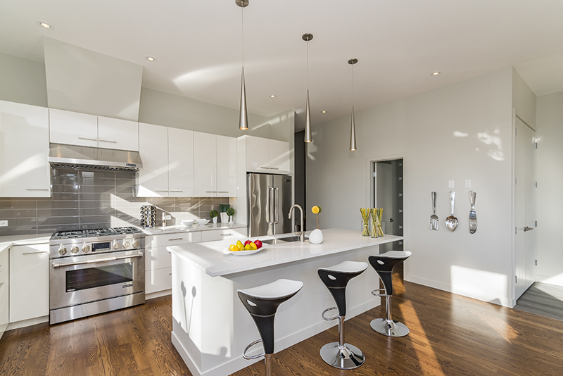 modern open kitchen layout with whit cabinets and silver pendant lights