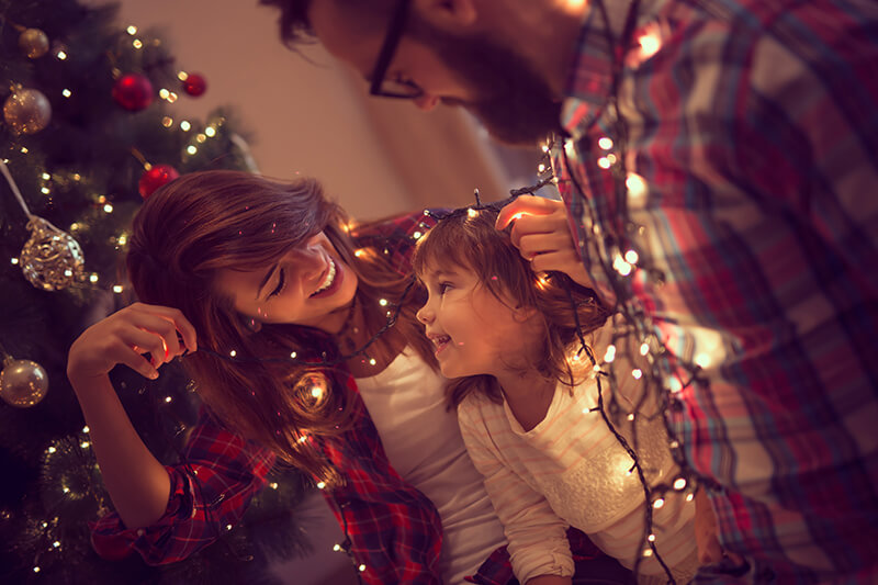 Mother and daughter holding Christmas lights