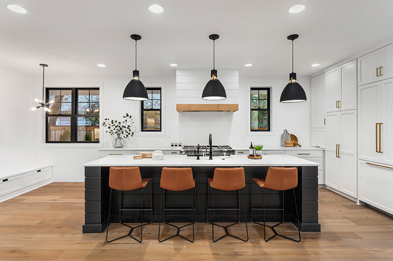 kitchen island with four brown chairs and three black pendant lights