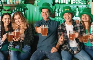 5 people wearing green hats and holding beers