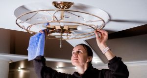 woman cleaning ceiling light fixture