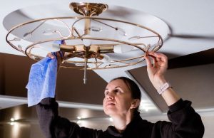 woman cleaning ceiling light fixture