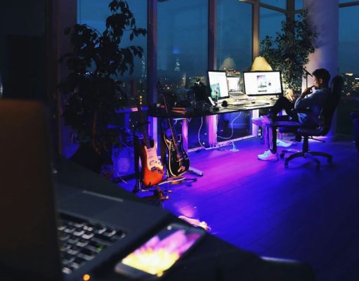 laptop foreground with man sitting by his desk in background