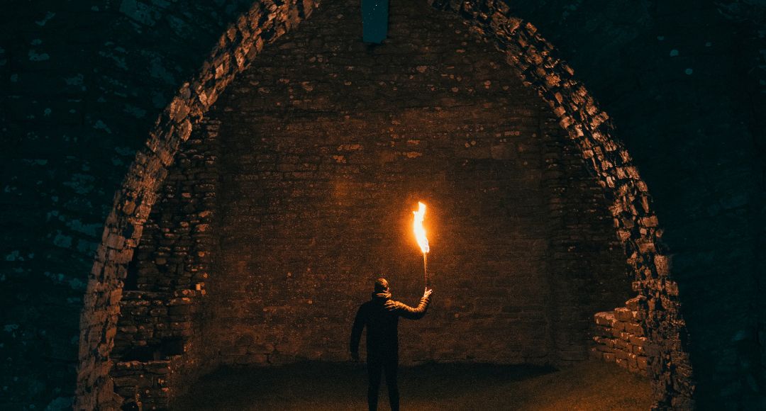 man holding a torch under brick walls