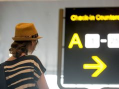 Woman looking at backlit airport sign
