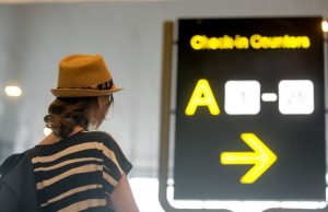 Woman looking at backlit airport sign