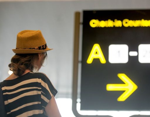 Woman looking at backlit airport sign