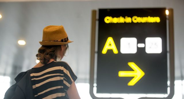 Woman looking at backlit airport sign
