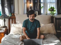 man with a laptop in the bedroom on his bed working