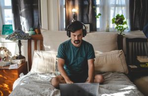 man with a laptop in the bedroom on his bed working