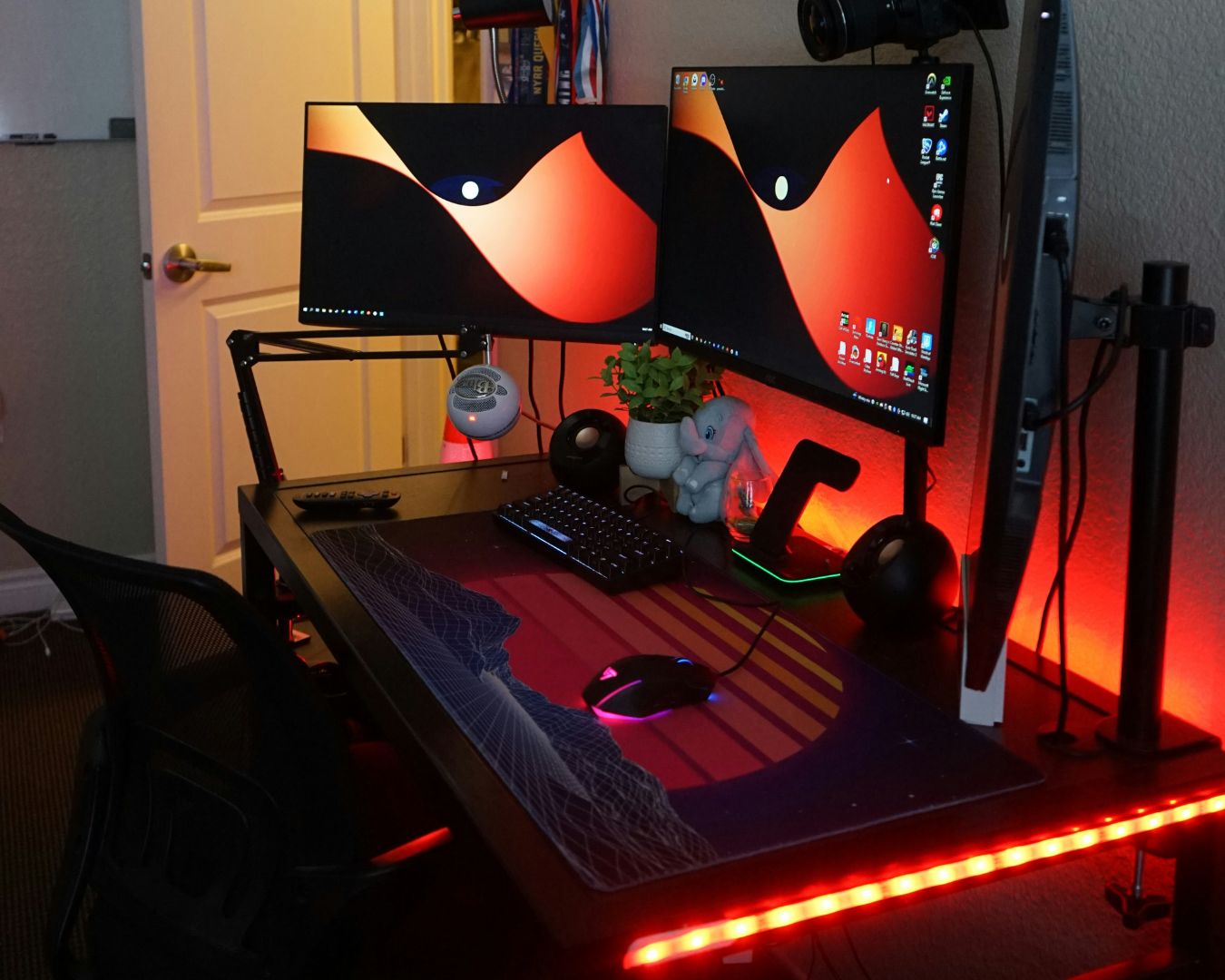 A PC gaming setup with orange strip light running along the edge of the desk.