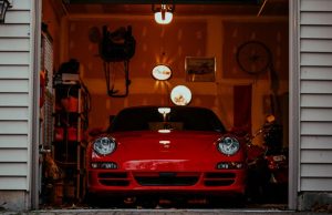 Front of an open garage showing a red car and a dim interior with a few warm lights.