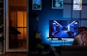 A person gaming in a dark room, his screen has a blue backlighting.