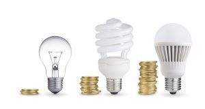 incandescent, CFL, and an LED bulb lined up with coins beside them.
