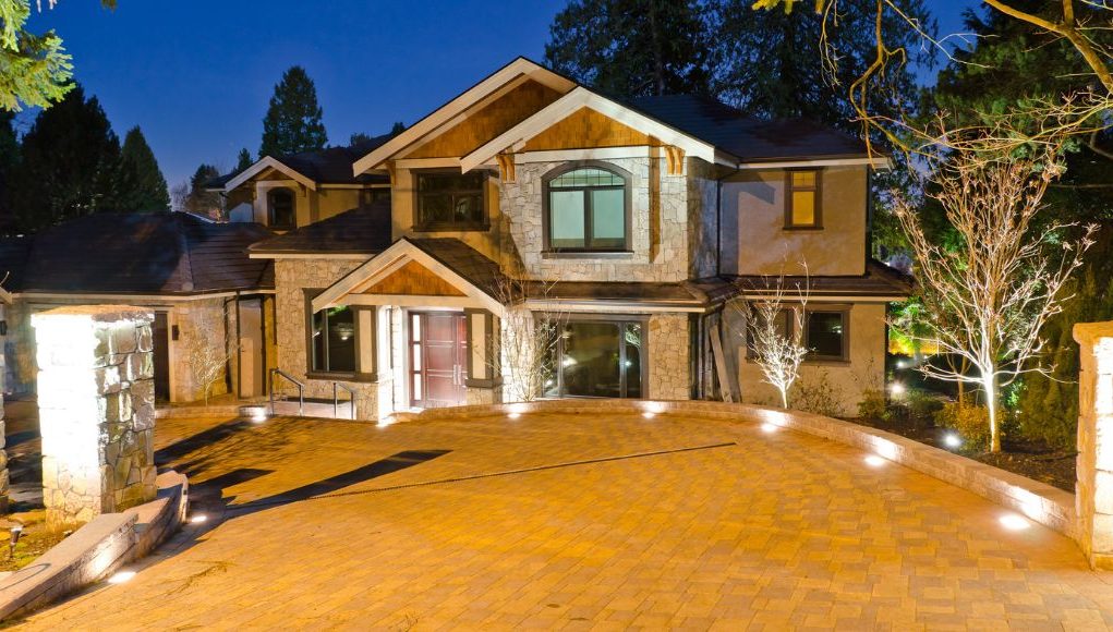 A house's driveway at night with all the lights on.
