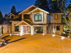 A house's driveway at night with all the lights on.