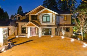A house's driveway at night with all the lights on.