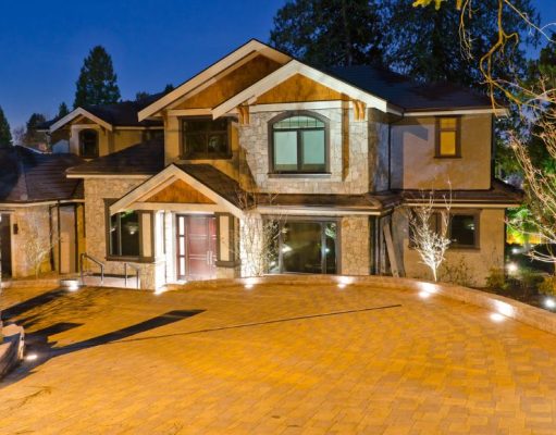 A house's driveway at night with all the lights on.
