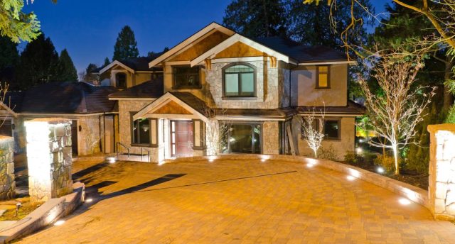 A house's driveway at night with all the lights on.