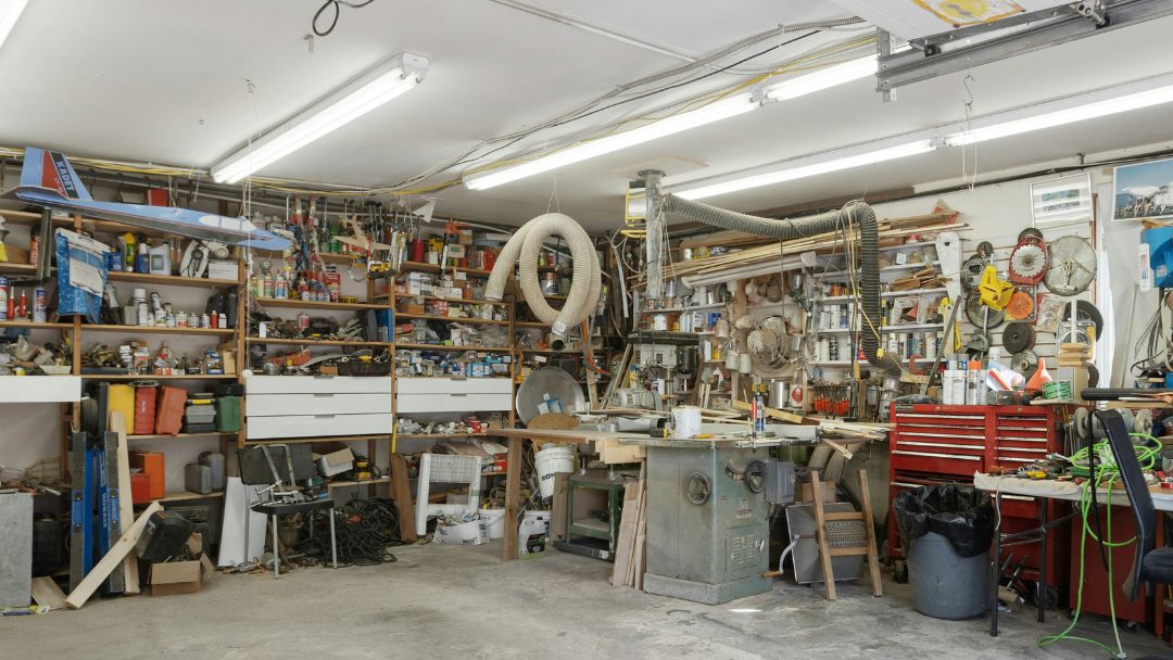 A brightly lit garage with walls lined with shelves filled with various tools and trinkets.