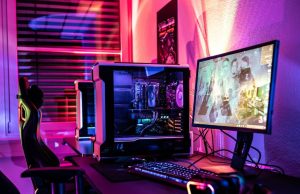 A gaming PC setup with bright red, orange, purple, and blue lights at the back of the monitor.