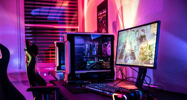 Best RGB Smart Lighting Products for Epic Gaming Setups A gaming PC setup with bright red, orange, purple, and blue lights at the back of the monitor.