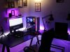 A PC setup in a dim room with a warm overhead light and a purple under desk lighting.