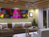 Living room with an L-shaped sofa and colourful painting on the wall and a hanging chandelier at the center.