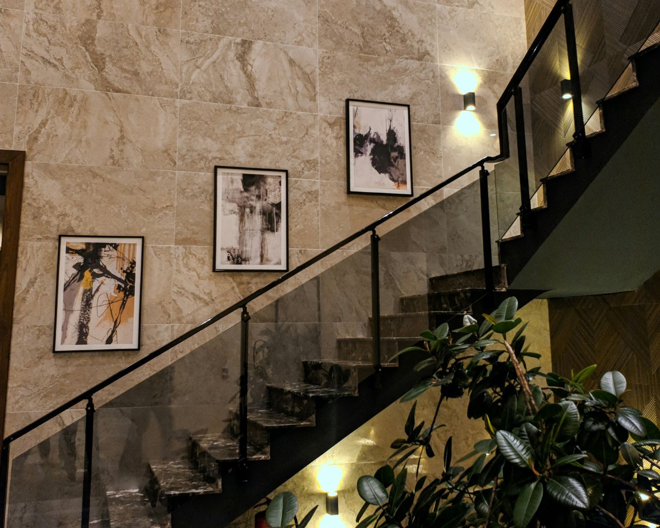 A dark staircase by a marble-tiled wall with a few up/down wall lights.
