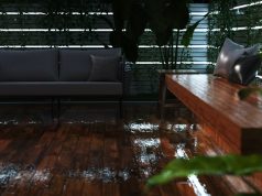 An outdoor deck that's wet from rain with multiple strip lighting on the perimeter wall.