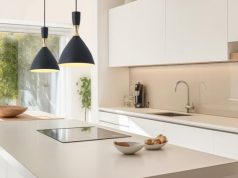 A modern kitchen with an island and two hanging pendants over it.