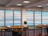An open office space with two long wooden desks near two large windows.