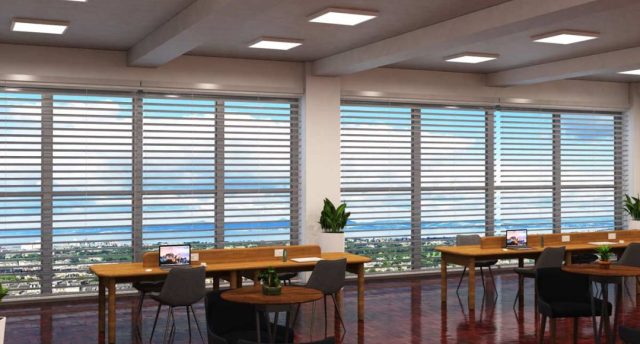 Smart Automation & Controls in Commercial Spaces An open office space with two long wooden desks near two large windows.