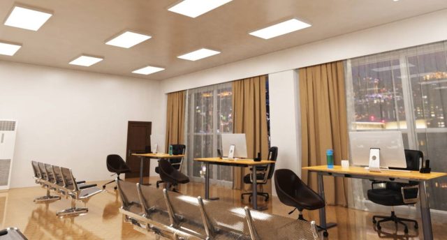 Smart Office Lighting: Designs that Boost Productivity & Comfort An open office space with three desks near two big glass windows and multiple LED panel lights on the ceiling.