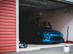 Best Smart Lighting Options for Your Garage A blue car is parked inside an open dark garage.
