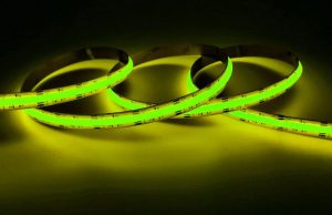 How to Control Your LED Strips with Apps & Voice A lit up yellow-green strip light in a dark room.