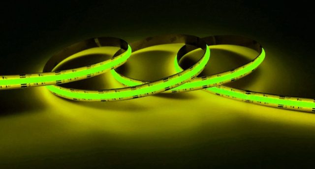 How to Control Your LED Strips with Apps & Voice A lit up yellow-green strip light in a dark room.