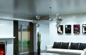 A living room with white sofa and black pillows and a silver hanging statement light.