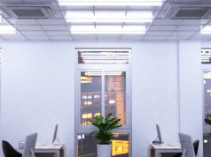 An office with windows overlooking a city, its ceiling is installed with multiple tube lights.