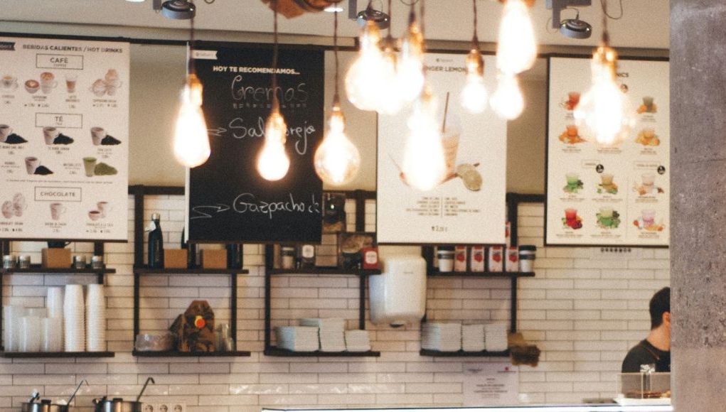 Image of a cafe menu with multiple warm light bulbs hanging from the ceiling.