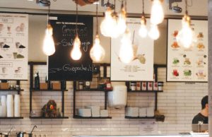 Image of a cafe menu with multiple warm light bulbs hanging from the ceiling.
