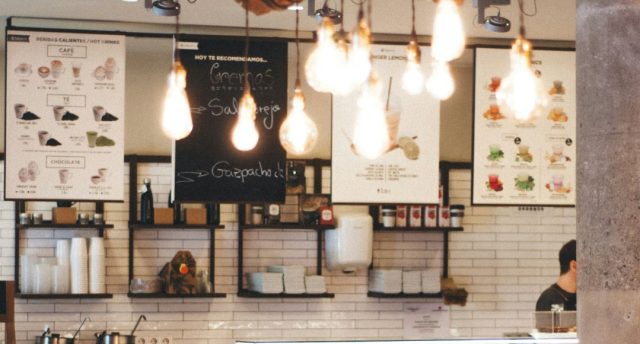 UK Lighting Regulations for Businesses Image of a cafe menu with multiple warm light bulbs hanging from the ceiling.