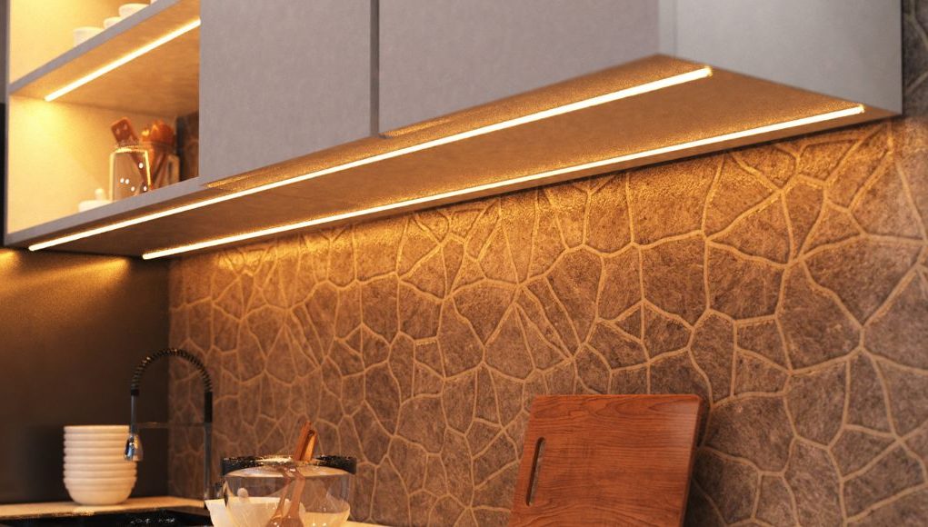 A kitchen countertop with visible under-cabinet LED strip lights with a warm glow.