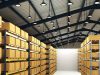 An image of a warehouse with shelves filled with boxes and the ceiling filled with high bay lights.