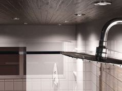 Best LED Bulbs for Bathrooms: Brightness, Colour & Efficiency A closeup of a showerhead in the foreground, multiple downlights on the wooden ceiling, and the upper part of the bathroom walls.