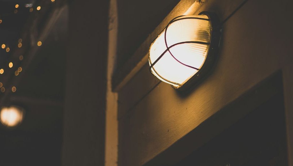 A bulkhead light with a warm glow installed in a dark outdoor space.