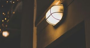 A bulkhead light with a warm glow installed in a dark outdoor space.