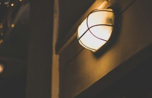 Indoor vs Outdoor LED Bulkheads: What’s the Difference & Which Should You Choose? A bulkhead light with a warm glow installed in a dark outdoor space.