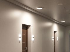 A hallway with two visible doors, both with wall lights on each side, and a single indoor bulkhead light on the ceiling directly above them.